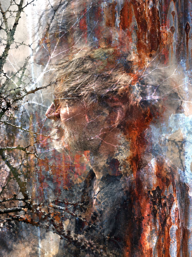 Portrait de Franke Feedcut en surimpression : un visage de profil, lunettes et barbe, pris dans un enchevêtrement de branches nues, de lichen et de coulées de rouille.
